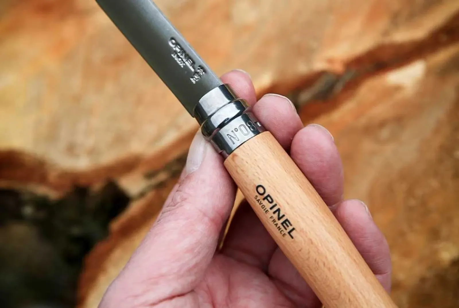 Opinel N08 Inox kniv med trähandtag mot rustik träbakgrund - framhäver rostfritt stål blad